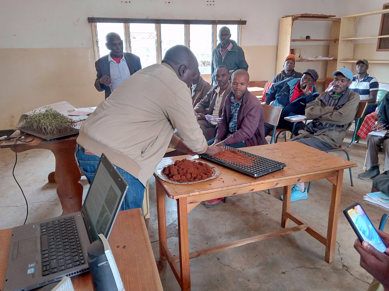 Trainer demonstrating seedling trays during an indoor session