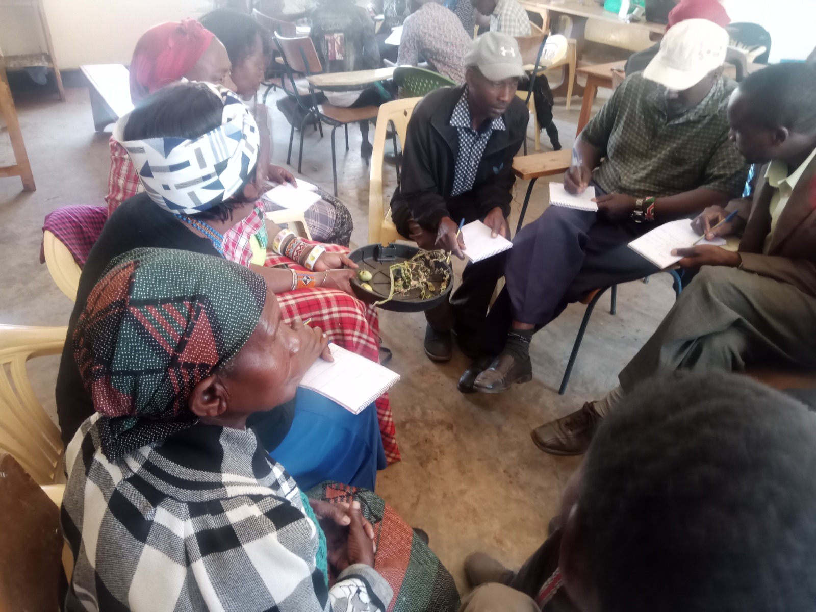 Farmers in a classroom examining crop samples and taking notes