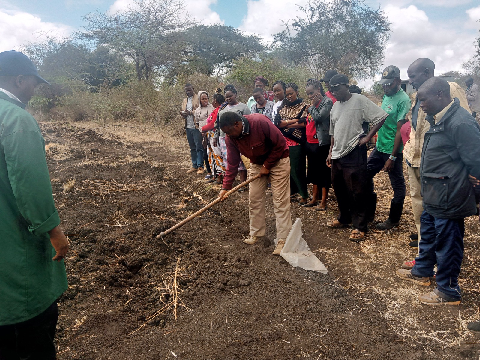 Group learning field preparation as one person hoes soil